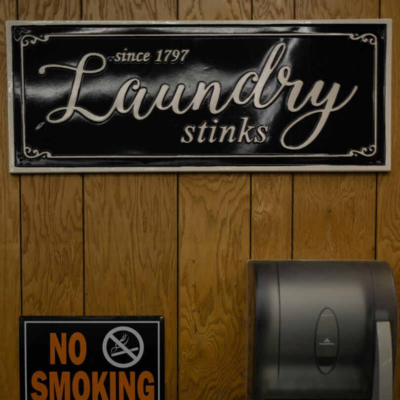 a sign on a laundry wall stinky washing machine fix