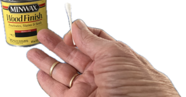 a person holding a cotton swab with liquid stain in a can