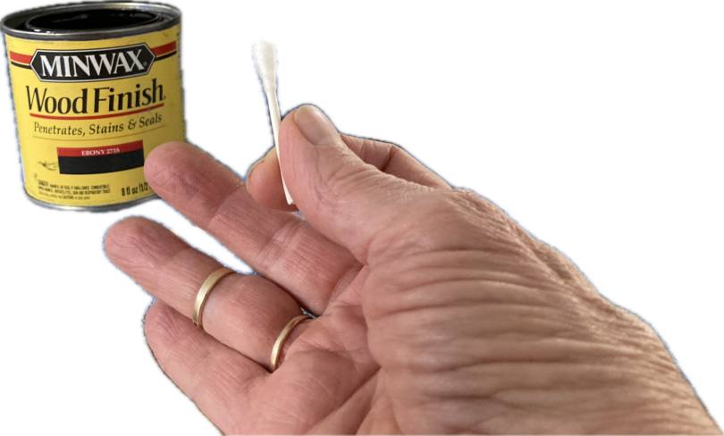 a person holding a cotton swab with liquid stain in a can