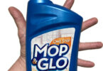 a hand holding a blue bottle of floor cleaner