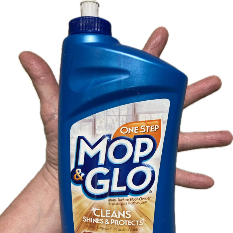 a hand holding a blue bottle of floor cleaner
