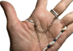 a hand with a beaded necklace