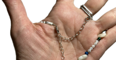 a hand with a beaded necklace