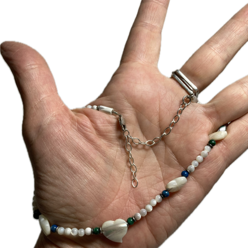 a hand with a beaded necklace
