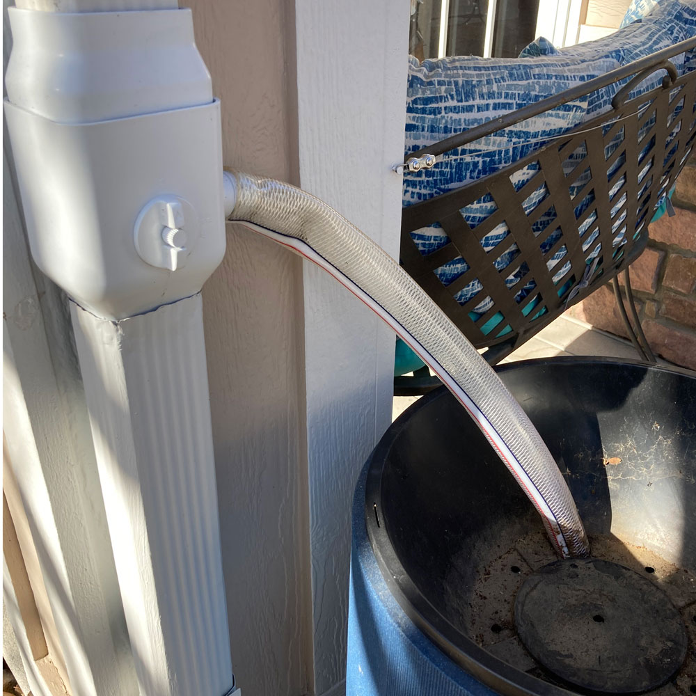 a down spout diverter and a hose going into a rain barrel