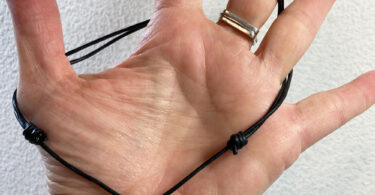 a hand with a sliding knot necklace