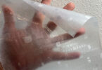 a hand holding a plastic sheet of window film