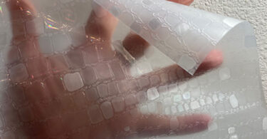 a hand holding a plastic sheet of window film