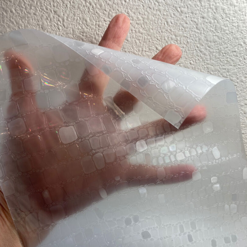 a hand holding a plastic sheet of window film