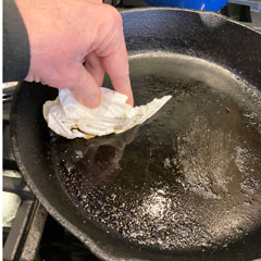 wiping oil from a cast iron skillet for cleaning